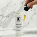 Hand holding dropper above Golden Glycolic night serum bottle on marble surface