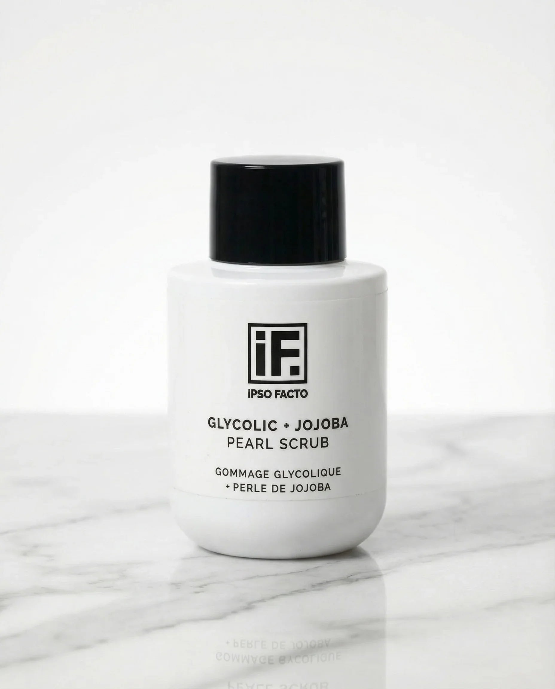 Glycolic and jojoba pearl scrub bottle on marble surface, minimalist skincare product