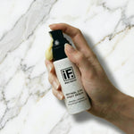 Hand holding retinol 2.5% night serum bottle on white marble background