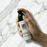 Hand holding retinol 2.5% night serum bottle on white marble background